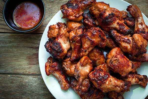 Chiken Wings on a plate with a dish of dipping sauce next to it.